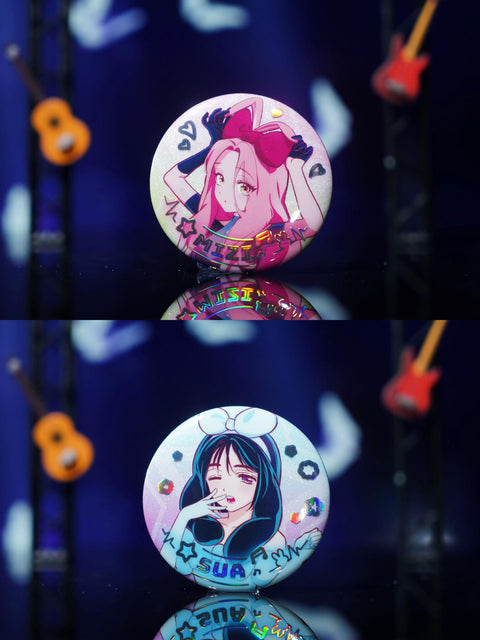 A detailed shot showcasing the Mizi and Sua badges, featuring pink and blue character-themed colors with a shimmering holographic finish.