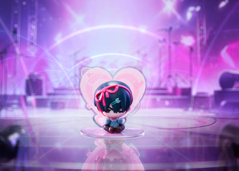 Chibi Ivan figure featuring a red ribbon headpiece, sitting pensively in front of a pink heart-shaped concert backdrop.