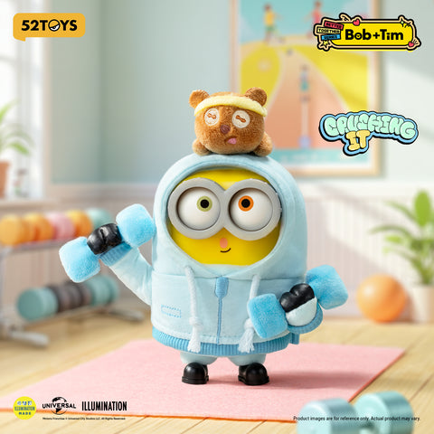 Minion Bob in a light blue fitness hoodie holding blue plush dumbbells, with Tim wearing a yellow headband on his head.