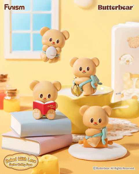 Butterbear “Baked With Love” figures posed with kitchen props. One bear holds an egg, another reads a red recipe book, one balances on a rolling pin, while another twirls a whisk. Each cub embodies playful baking tasks, styled with cute details, pastel accents, and a warm, cozy culinary atmosphere.