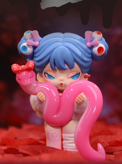 A fantasy-themed collectible figurine from the "DODO NAMI Paradise of Doom" series features a character with blue twin-bun hair, adorned with pink bows and eyeball decorations. She has striking blue eyes and a mischievous expression. She holds a large, glossy pink snake with a red bow on its head, wrapped around her body. Dressed in a fluffy pink outfit with bandaged legs, she stands against a red-hued background, exuding a mix of eerie charm and playful mystery.