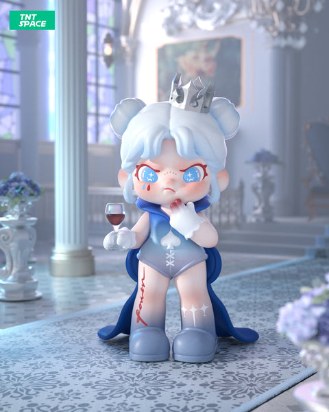 A 3D-rendered Dora figurine with an icy blue theme stands in an elegant palace-like setting. The character has light blue hair styled in two buns, a silver crown, and a determined expression with red teardrop-shaped marks under its eyes. It wears a blue cape, a bodysuit with a spade symbol, and gradient blue boots with white star-like patterns. The character holds a glass of red wine in one hand and touches its lips with the other. The background features grand pillars.