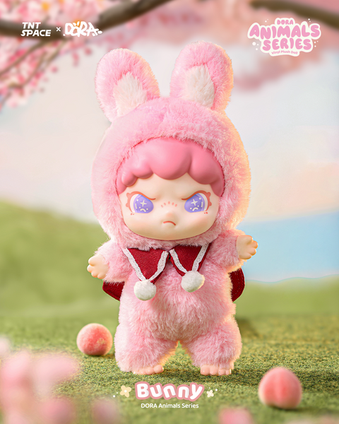A cute doll in a fluffy pink bunny outfit complete with tall ears and pom-pom ties. Its short pink hair peeks out, while glittering purple eyes add charm. The soft costume creates a gentle spring vibe as the figure stands barefoot on grassy ground with scattered pastel balls beneath a cherry blossom tree.