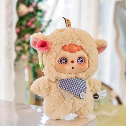 Lamb Doubao plush in a soft cream-colored fuzzy suit with round lamb ears, a pink flower accent, and blue gingham bib. Its wide sparkling eyes show lamb reflections, and rosy cheeks highlight its gentle, sheepish expression, adding pastoral sweetness to the series.
