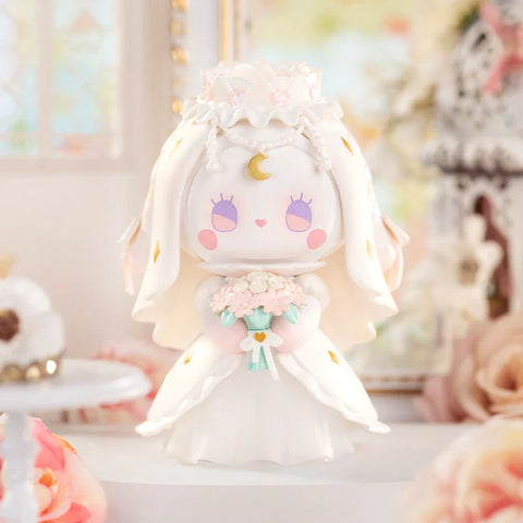 A graceful figurine from the "Emma Secret Forest: Beloved Series" stands in an elegant wedding-inspired setting. The character wears a flowing white gown adorned with gold accents, a delicate lace veil, and a pearl-like headpiece. A golden crescent moon decorates its forehead, and it holds a pastel bouquet with a heart-shaped ribbon. Soft pink roses, ornate frames, and vintage décor in the background enhance the dreamy, romantic atmosphere of this celestial-inspired figure.