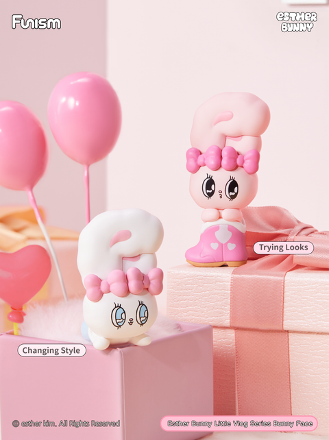 Two Esther Bunny figures styled in pink and purple, one wearing heart-decorated boots and striking a fashion pose, the other flipping upside down with a sweet smile. They are displayed on pink gift boxes surrounded by balloons, evoking a playful dressing-up theme.