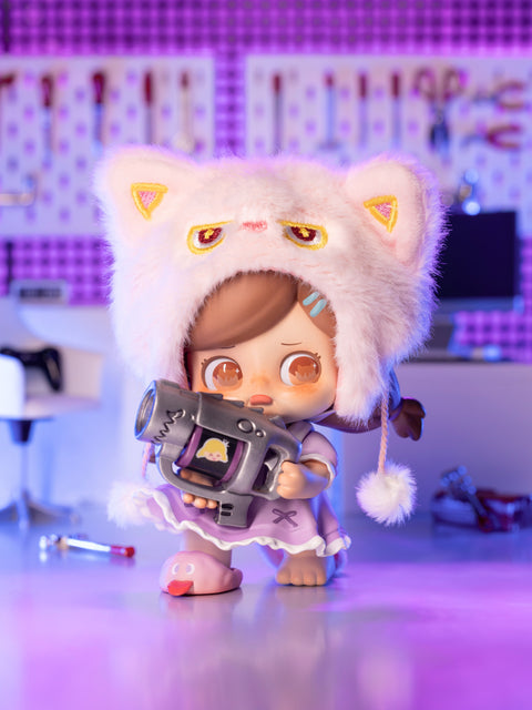 KO Quietness figure features a girl in a white outfit with oversized fluffy cat-ear hat, holding a toy gun. She wears slippers and stands in a pastel-lit lab with surgical tools, creating an eerie contrast between her soft attire and intimidating prop. The design blends innocence with unsettling strangeness.