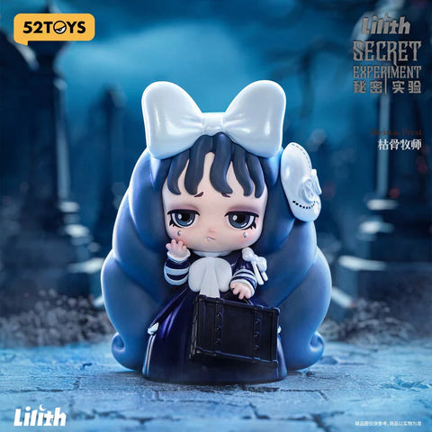 A gothic-style figurine from the 52TOYS "Lilith Secret Experiment" blind box series, titled "Skeleton Priest." The character features a solemn expression, long flowing dark blue hair with curled ends, and a large white bow atop her head. She wears a dark dress with white stripes and holds a black book-like object. A skull accessory is pinned to her side. The eerie, misty graveyard background adds to the haunting and mysterious atmosphere.
