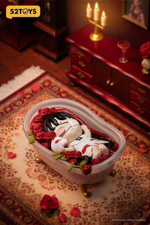 Close-up of the secret chaser figure “Rose Ritual Bath” from 52TOYS’ Lilith: The Century of Mary series. The character lies peacefully in a small pink bathtub surrounded by red roses and petals. Dressed in white with red markings, she holds a skull and wears a eyepatch, suggesting a symbolic or ceremonial act. The detailed setting includes a patterned rug, dark wood furniture, and candlelight, creating a rich, vintage atmosphere.