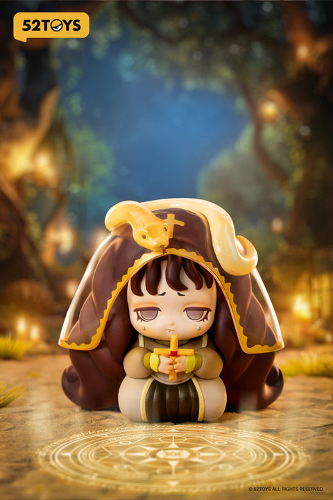 Close-up of the “Secret Prayer” figure from 52TOYS’ Lilith: The Century of Mary series. The character kneels solemnly within a glowing ritual circle, holding a cross close to her chest. She wears a hooded brown and gold robe, with a pale yellow snake resting atop her head. Her expression is weary and tearful, evoking a sense of burdened devotion. The warm, mystical forest setting is softly lit by candles, adding an air of sacred secrecy and occult symbolism.