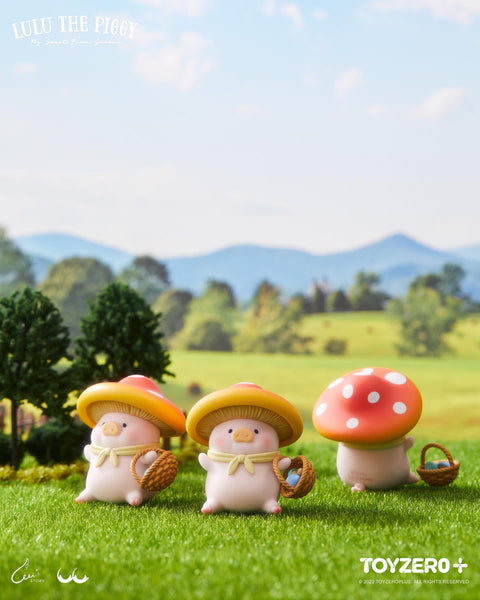 Two LuLu piggies wearing red-and-white polka dot mushroom hats and carrying small woven baskets, walking through the grass.