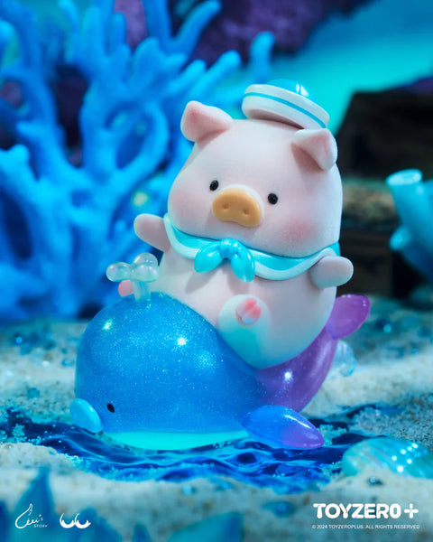 A super secret chaser figure from the LuLu The Piggy Ocean Series by 52TOYS and ToyZero+ features LuLu riding a sparkling blue and purple whale balloon. The pig wears a blue sailor hat and scarf, looking cheerful as it sits atop the glossy, glitter-filled whale in an underwater scene with shells, coral, and gentle waves. This magical design captures the whimsy of ocean exploration in a dreamy, aquatic fantasy world.