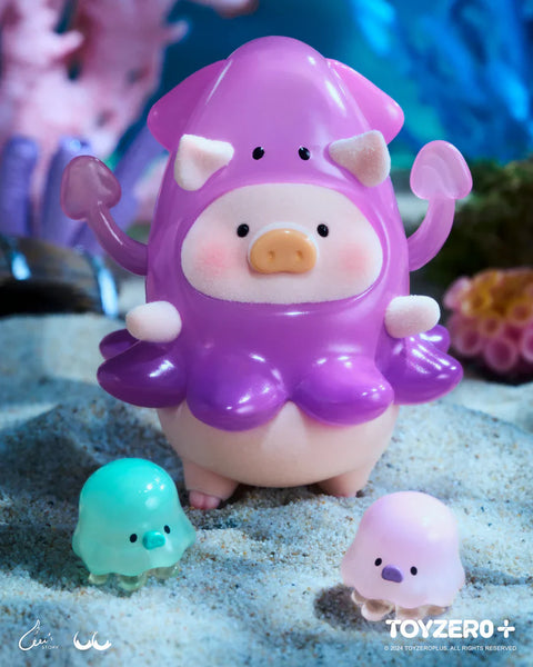 A LuLu the Piggy figure from the Ocean Series by 52TOYS and ToyZero+ is dressed in a vibrant purple squid costume, complete with extended tentacles and tiny black eyes on the hood. The pig’s soft face peeks out from the squid body, with a blush and a sweet expression. Two small jellyfish-like companions—one mint green and one pink—sit at its feet on a sandy seabed, surrounded by coral and underwater plants, creating a fun and whimsical deep-sea scene.