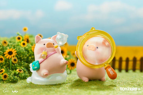 Two LuLu the Piggy figures from the Travel Series by 52TOYS and ToyZero+ are posed in a sunny field of sunflowers. One pig lounges on a cloud-like seat, holding a drink and a bubble blower, with a teal bag slung over its shoulder. The other pig stands nearby, peering through a large yellow magnifying glass labeled "LuLu." The scene evokes a playful, carefree summer day filled with exploration and imagination.