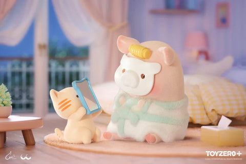 In this charming nighttime scene from the “Lulu the Piggy: Stay With You” blind box series, a piggy figurine enjoys a cozy self-care moment. Dressed in a mint-green robe with a facial mask and a yellow hair roller, the pig sits calmly as a tiny cat companion holds up a blue-framed mirror. Set in a softly lit bedroom with an open balcony view, a yellow checkered blanket, tissue box, and side table with a potted plant add warmth and detail to this adorable pampering session.
