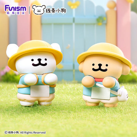 Two pups wearing yellow sun hats and blue school smocks with white name tags, standing in front of a blue garden gate.