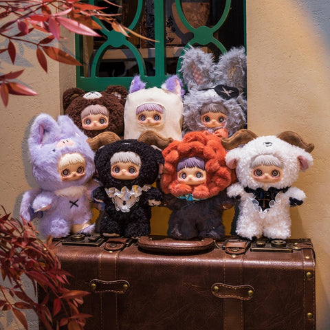 Seven assorted MayMei plush dolls from the Dark Forest series posed together on a vintage brown leather suitcase against a tan wall with a green lattice window.