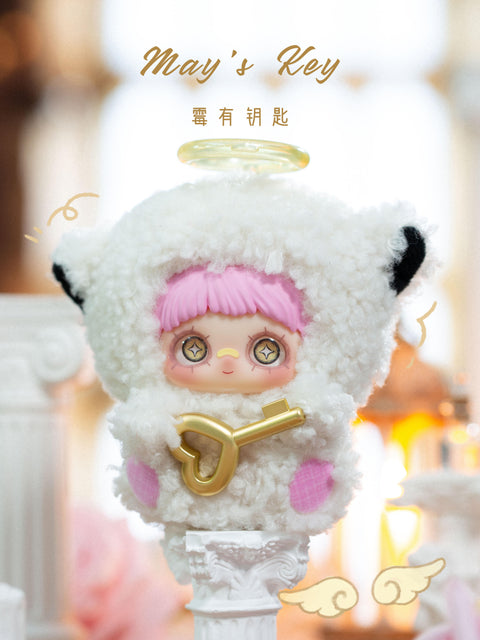 A plush figure stands elevated on a white decorative pedestal, wearing a white fuzzy hood with rounded ears and a translucent halo resting above the head. The character has pink bangs, large star-detailed eyes, and a gentle expression. A metallic gold key accessory is held across the front. The background shows blurred candlelight, soft drapery, and warm interior tones.