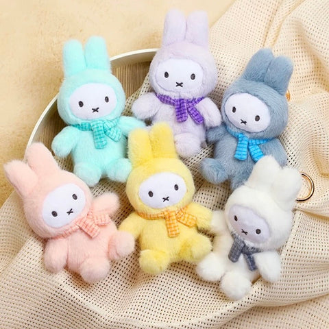 A full display image showing all plush bunny figures from the Miffy Macaron Series arranged together. The lineup includes blue, green, pink, purple, yellow, white, and the hidden chaser, each wearing a fluffy macaron-inspired outfit with scarves and upright ears.