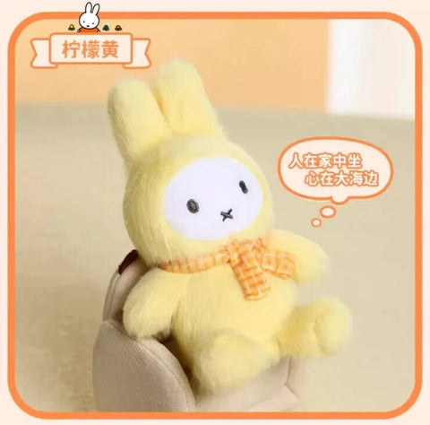 A pastel yellow plush bunny wearing a soft macaron-inspired costume with upright ears and plush texture throughout. The figure has a white face, black dot eyes, an X-shaped mouth, and a yellow knitted scarf that adds warmth and cheerful softness.