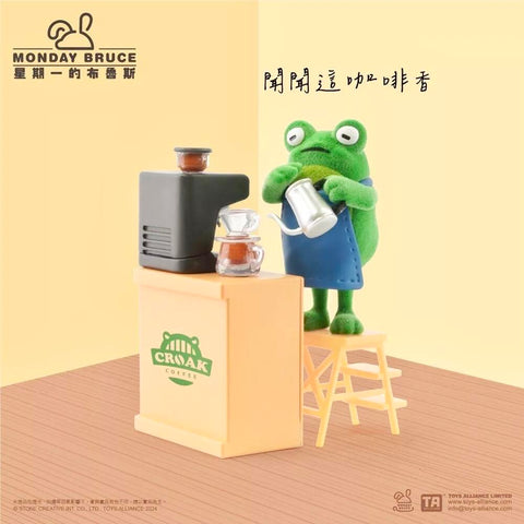 A green frog barista in a blue apron pours coffee beside a Croak Coffee machine and counter. The playful design highlights the smell of fresh coffee, setting the pre-work café mood of this blind box figure.