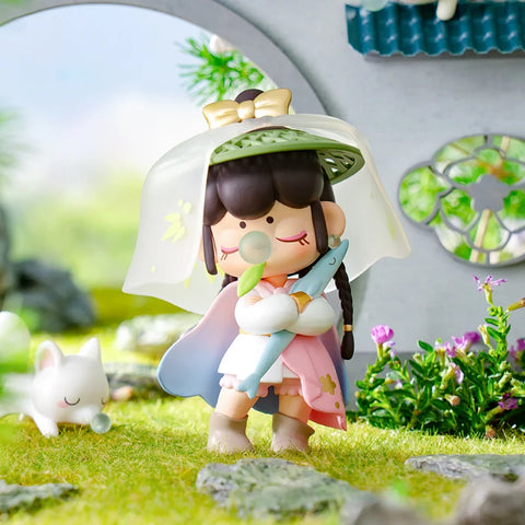 A serene collectible figurine from the "Nanci Blooming Girl" series features a girl dressed as a warrior in a pastel pink and white outfit. She holds a blue fish-shaped sword and wears a translucent veiled hat adorned with a golden bow. Her braided hair and closed eyes add to her peaceful expression. A small white fox with a bubblegum bubble rests nearby. Set in a lush garden with a traditional Chinese architectural backdrop, the scene exudes tranquility and elegance.