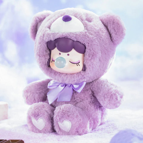 A charming collectible figurine from the "Nanci Colorful Chocolate Cutie Bears" plush series features a character dressed in a soft, lavender-purple bear suit with a matching satin bow. The figure has a peaceful expression with closed eyes and a bubblegum bubble, while heart-shaped details accent its plush paws. Set against a dreamy, cloud-like backdrop with hints of chocolate, this scene radiates a cozy and whimsical aesthetic, reminiscent of a sweet taro cocoa treat.