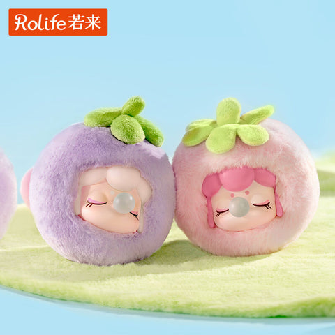 Two Nanci Fruit Mood plushies sit side by side, one styled as a purple mangosteen and the other as a pink strawberry. Each has a green leafy felt crown, closed eyes with long lashes, and a bubblegum bubble. Their cozy fuzzy textures highlight the dreamy fruit character pairing.
