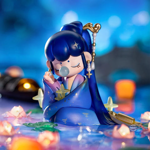 Nanci sitting in front of a bridge with long blue hair. She's holding one of her long dangling earrings. He other hand is hidden but it is implied she could be holding a star.