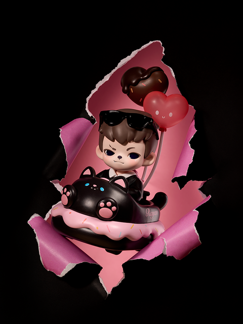 A figure rides a black donut-shaped car with pink paw details and heart balloons attached. Wearing sunglasses and a white shirt, it appears to burst through pink paper, revealing a playful and romantic theme.