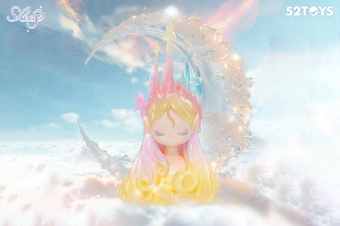 A 52Toys “Sleep: Life of Fantasies” figurine titled “Aurora Isle” features a peaceful character with pastel blonde and pink hair, eyes gently closed. She wears a majestic crown of translucent towers, stars, and moons in soft gradient colors. Set against a dreamy backdrop of clouds, sky, and a glowing crescent moon, the figure radiates celestial calm.