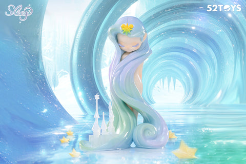 A figurine from the 52Toys “Sleep: Life of Fantasies” series, featuring a serene, pastel-haired character with eyes closed, standing gracefully with long, swirling hair that flows to the base. The background is a dreamy, icy tunnel with glistening textures and a reflective surface, dotted with glowing yellow stars and a delicate castle sculpture at her feet.