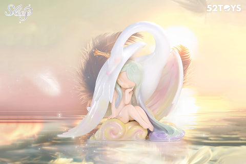 A figurine from the 52Toys “Sleep: Life of Fantasies” series titled “Mild Zephyr” features a tranquil character seated on a pastel cloud, eyes closed in rest. A graceful white swan with a golden crown gently curves around her protectively. The golden light, feathers, and calm water reflect a serene dreamscape.