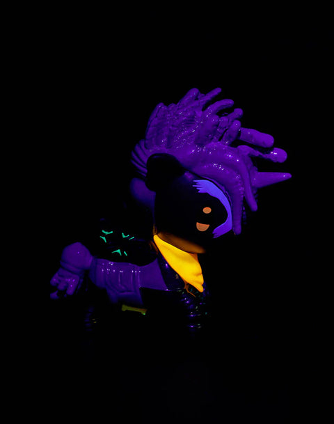 The Tokidoki Arcane Unicorno Ekko figure is shown under blacklight, causing neon greens, blues, and UV-reactive symbols to intensify. Chrome areas glow with cool reflections while Ekko-themed hair streaks and facial markings appear brighter, emphasizing the figure’s ultraviolet-enhanced details.