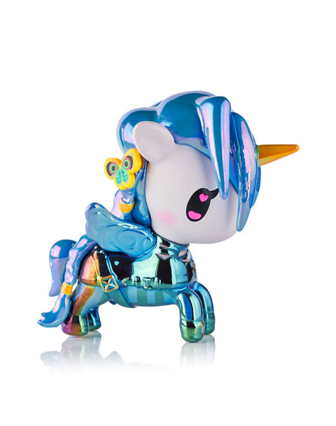 A Tokidoki Arcane Unicorno figure inspired by Jinx stands on a white backdrop. The design includes Jinx’s blue braids, pink and blue costume colors, stitched straps, and chrome accents. Sculpted textures reference her belts, explosives, and accessories, reinterpreted into the Unicorno silhouette.