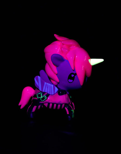 The Vi Unicorno glows under blacklight, revealing neon outlines across her suit, a bright yellow glowing horn, and deep purple shadows across her body. Her hot-pink mane becomes intensely fluorescent, and the teal geometric markings along her armor illuminate sharply against the dark background.