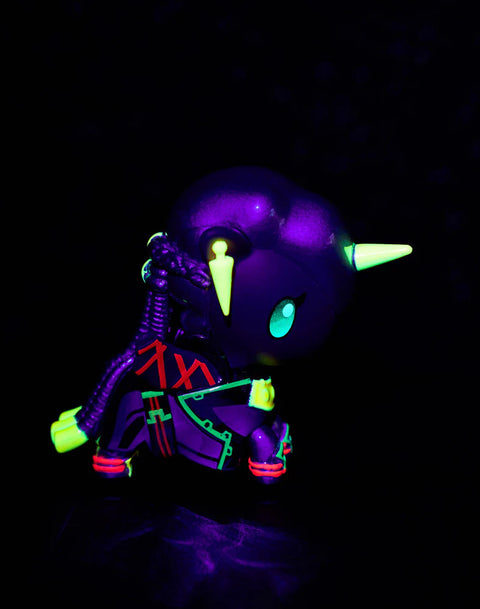 Under blacklight, the Ambessa Unicorno displays glowing green outlines across the armor while the helmet and horn shine in pale neon yellow. The deep shadows intensify the figure’s purple and blue tones, and the red markings on the shoulder illuminate sharply against the dark, high-contrast background.