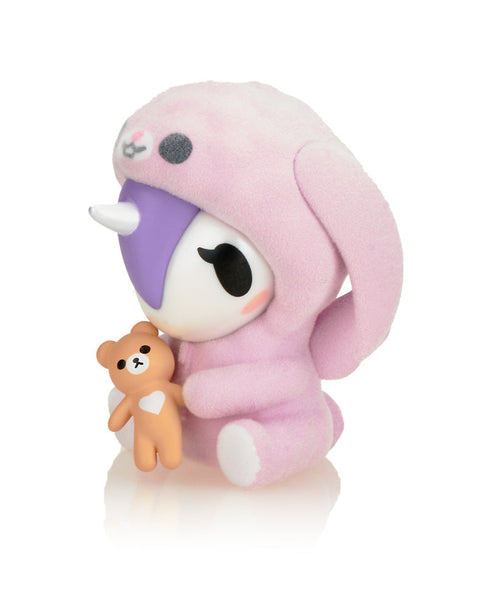 A detail view of Cuddle Bunny, featuring a soft pink flocked texture and a miniature brown teddy bear accessory with a white heart detail.