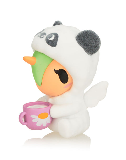 Snuggles the Unicorno, wearing a white and grey panda onesie and holding a pink coffee mug with a white daisy design.