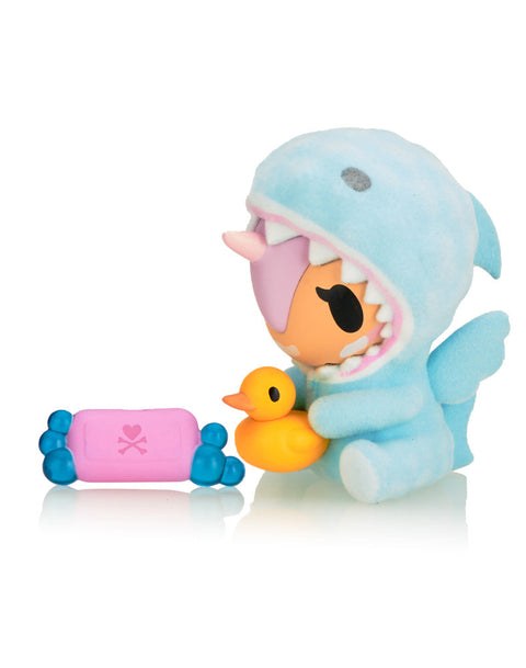 Sudsy the Unicorno, featuring a light blue shark onesie with a soft texture, accompanied by a pink soap bar and a yellow rubber ducky.