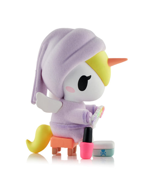 A rare collectible Unicorno figure with a metallic gold body, wearing a white towel wrap and holding a miniature gold hairdryer.