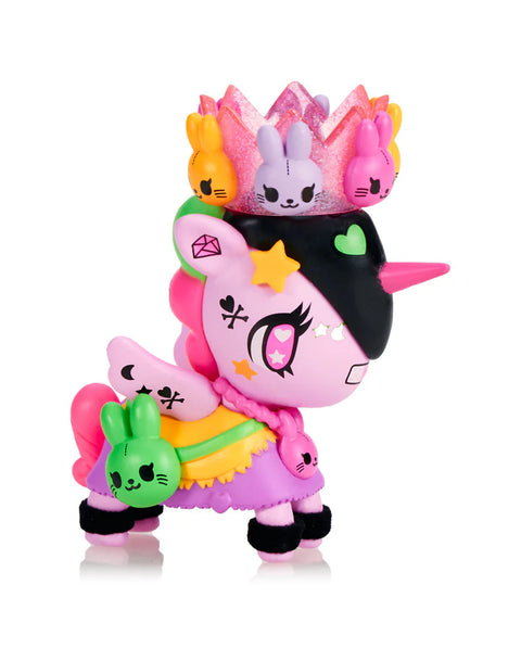 A pink Unicorno with a black side-swept mane wears a glittery crown filled with colorful bunny figures. Additional bunny characters rest on its back and legs. The figure features bright star markings, crescent shapes on the wings, and layered pastel skirts. Its bold eye design highlights the playful rabbit-themed chaser identity.