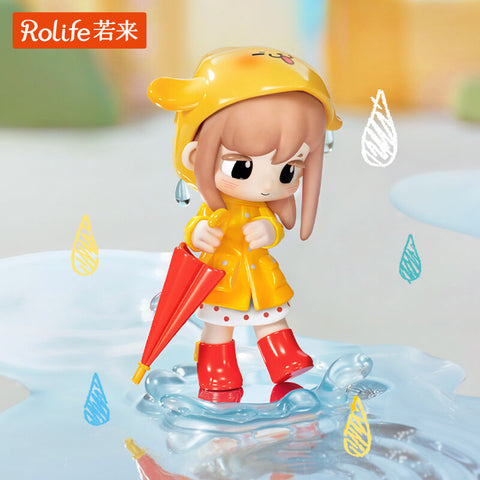 A girl in a bright yellow raincoat and matching hood leaps into a puddle, holding a red umbrella by her side. Red boots splash water dramatically as droplets are sculpted around her base. The piece highlights playful rainy-day moods, with bold colors and movement bringing the diary theme to life.