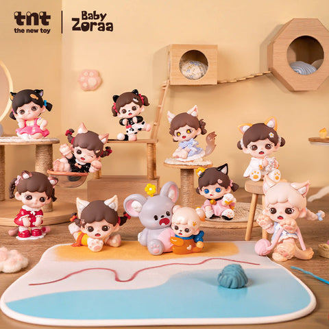 A complete lineup of Baby Zoraa’s Meow Cat Face Mini Series figures is arranged on a beige cat-themed playroom set. Ten cat eared characters in various poses and pastel outfits sit and play among wooden platforms, yarn toys, and a soft mat designed to look like a poolside or beach scene.