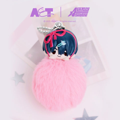 Plush keychain figure of Ivan from Alien Stage, showing a chibi character head with dark blue hair and pink ribbon details atop a soft pink pom-pom body. Finished with a silver ball chain, the product is photographed against a clean pastel background.