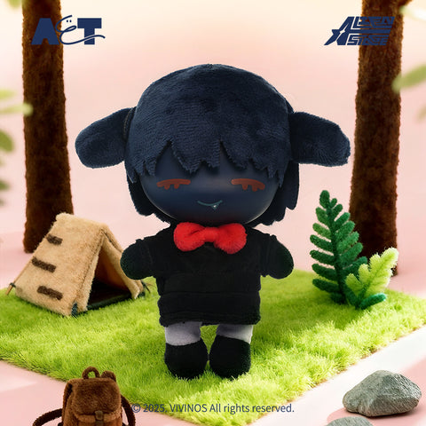A dark, navy blue plush Ivan with closed eyes and a bright red bowtie, standing in front of a miniature campsite with a tent and backpack.