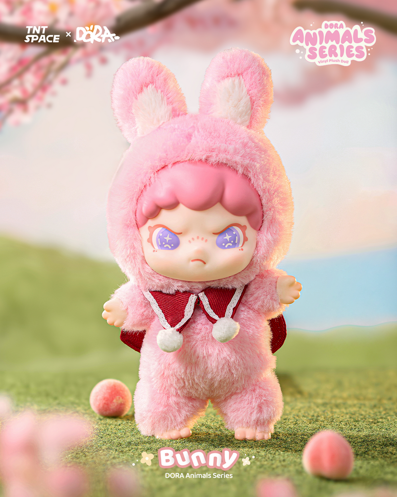 A cute doll in a fluffy pink bunny outfit complete with tall ears and pom-pom ties. Its short pink hair peeks out, while glittering purple eyes add charm. The soft costume creates a gentle spring vibe as the figure stands barefoot on grassy ground with scattered pastel balls beneath a cherry blossom tree.