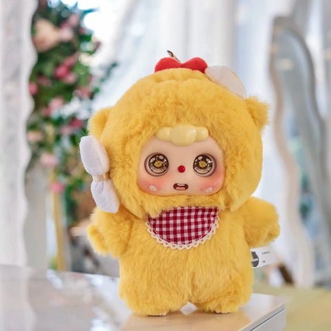 Chick Doubao plush in a bright yellow fluffy suit with a red gingham bib and apple stem accent on its hood. Its round eyes shine with chick-themed reflections, cheeks are blushed, and its playful, curious pose makes it look like a tiny baby animal student ready for class.