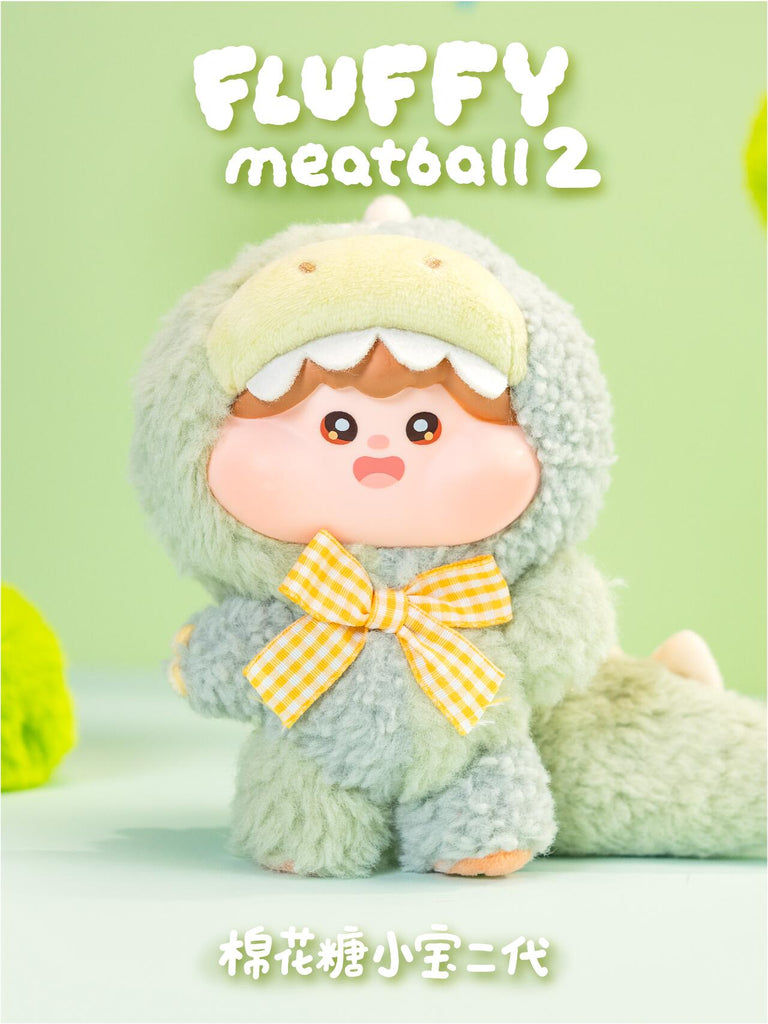 Green dragon plush character with a fuzzy textured outfit, large dragon tail, and gingham yellow bow tie. Its childlike face with wide eyes adds an innocent, magical vibe that captures the fantasy-inspired theme of the series.