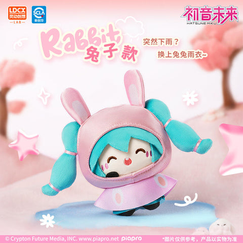 Rabbit-style Hatsune Miku plush in a pastel pink raincoat hood with floppy bunny ears and paw details. Her turquoise twin tails peek out as she smiles happily. Posed on a puddle with doodle stars and a pink cherry blossom-inspired background, the design radiates springtime sweetness and cheerful energy.